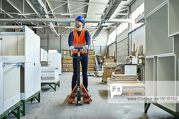 Arbeiter fährt auf Hubwagen in der Fabrik