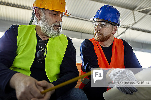 Two men working on plan in factory