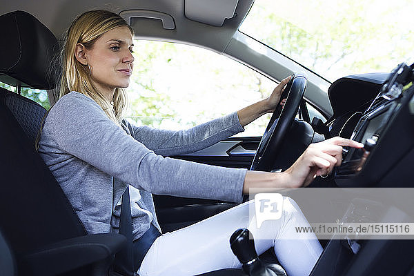 Junge Fahrerin wählt in ihrem Auto einen Radiosender