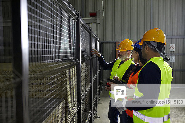 Arbeiter stehen am Gitter in der Fabrik und reden