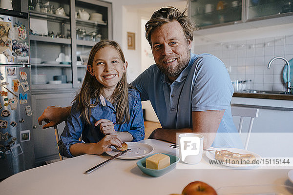 Portrait of father and daughter at home sitting at breakfast table