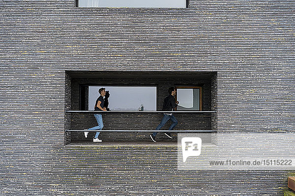 Zwei junge Männer rennen auf einem Balkon eines Gebäudes
