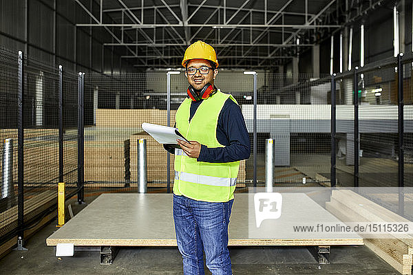 Porträt eines lächelnden Arbeiters mit Zwischenablage im Fabriklager