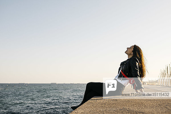 Junge Frau sitzt im Hafen auf dem Boden