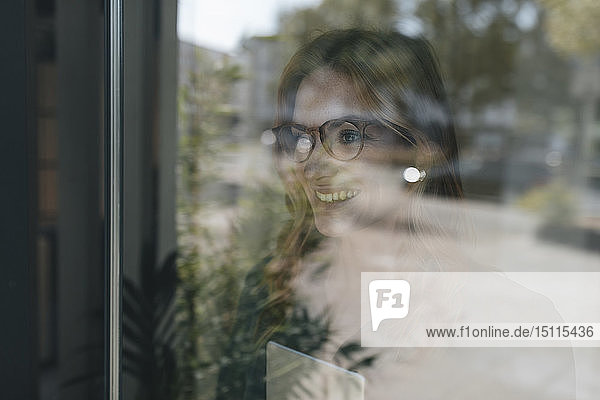 Lächelnde Geschäftsfrau hinter Fensterscheibe