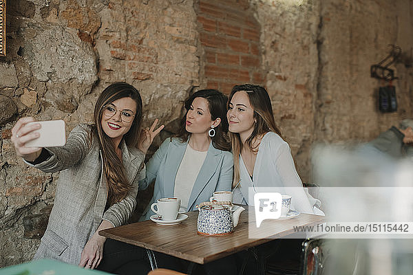 Three young women taking a selfie in a cafe
