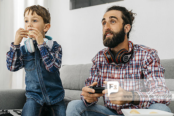 Portrait of father and son on the couch playing computer game