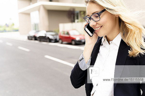 Lächelnde junge Geschäftsfrau am Telefon beim Überqueren der Straße