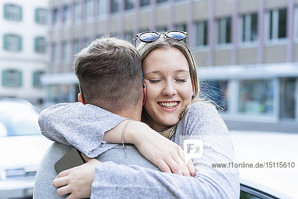 Porträt einer glücklichen jungen Frau die ihren Freund umarmt