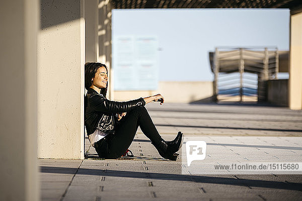 Junge Frau sitzt auf dem Boden und genießt das Sonnenlicht