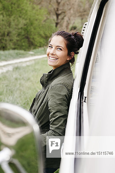 Laughing young woman leaning on camper