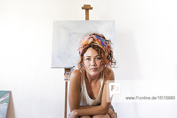 Porträt einer jungen Malerin im Kunstatelier neben einer leeren Leinwand