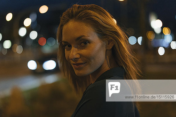 Porträt einer jungen Frau in der Stadt bei Nacht