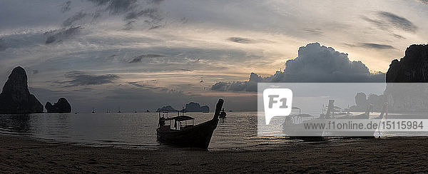 Thailand  Krabi  Strand von Railay  Bucht mit Langschwanzbooten  die bei Sonnenuntergang auf dem Wasser treiben