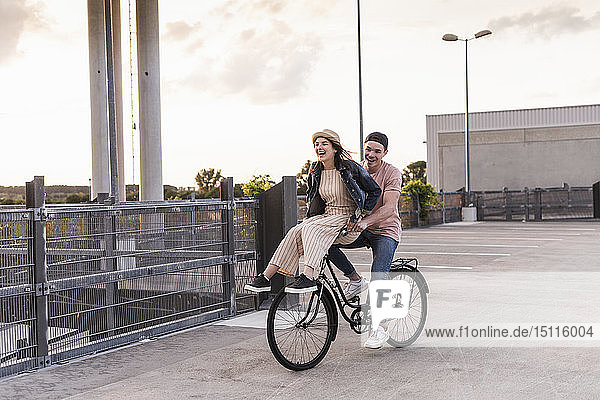 Happy young couple together on a bicycle on parking deck