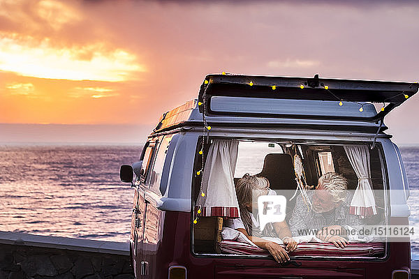 Älteres Ehepaar reist in einem Oldtimer-Van und liegt im Kofferraum