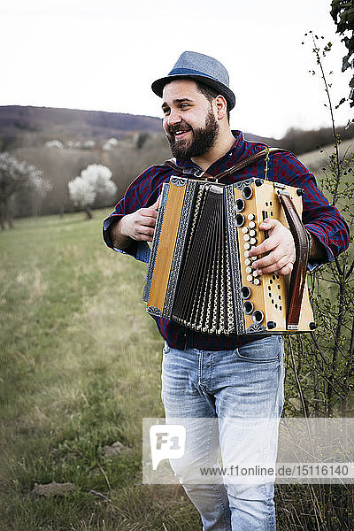 Portrait of bearded man playing accordion on a meadow