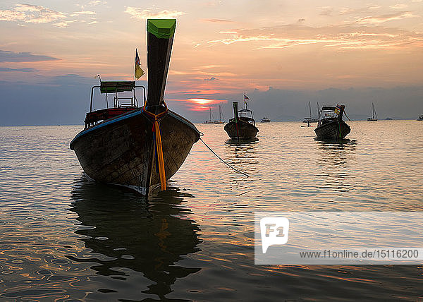 Thailand  Krabi  Bahnstrand  Langheckboote  die bei Sonnenuntergang auf dem Wasser treiben