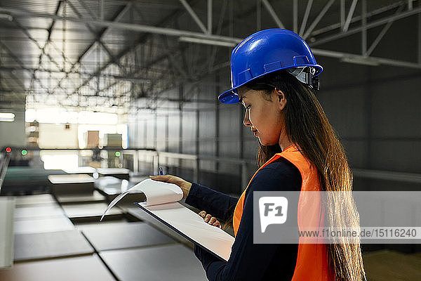 Arbeitnehmerin prüft Dokumente im Fabriklager