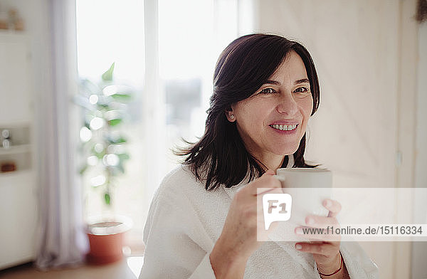 Mature woman in a bathrobe  drinking her morning coffee