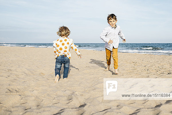 Junge und seine kleine Schwester spielen am Strand