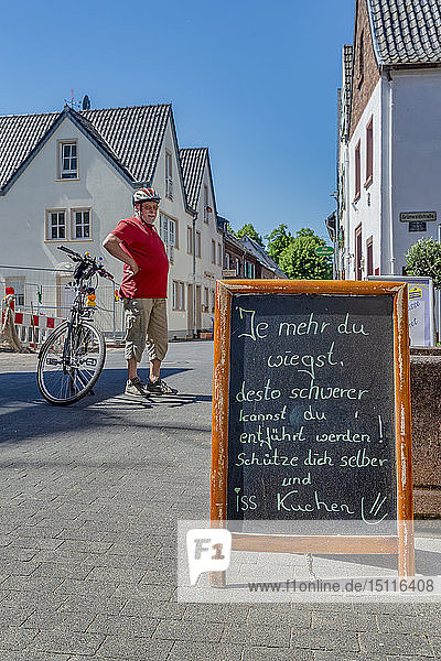 Deutschland  Zons  älterer Mann mit Fahrrad beim Ausruhen