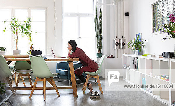 Woman using laptop at table in modern office