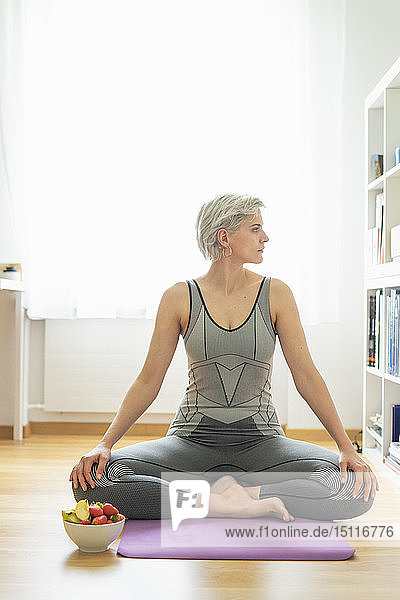 Woman practising yoga at home  having a healthy fruit snack