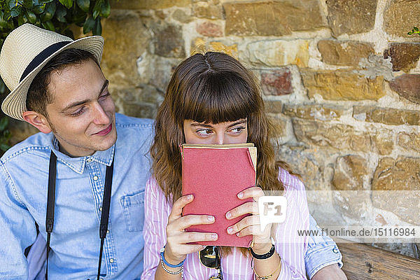 Junges Paar auf Städtereise  sitzt auf einer Bank und liest einen Reiseführer