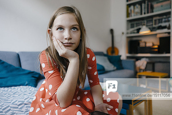 Porträt eines ernsten Mädchens  das zu Hause auf der Couch sitzt