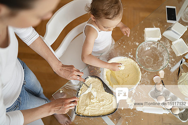 Draufsicht auf Mutter und kleine Tochter  die zu Hause in der Küche gemeinsam einen Kuchen backen