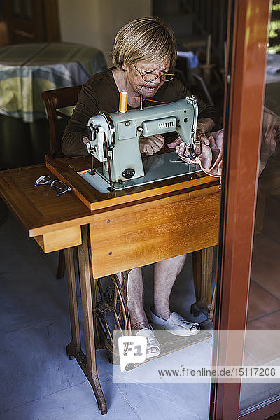 Ältere Frau benutzt zu Hause eine alte Nähmaschine