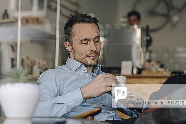 Erfolgreicher Geschäftsmann sitzt im Kaffeehaus und trinkt Kaffee