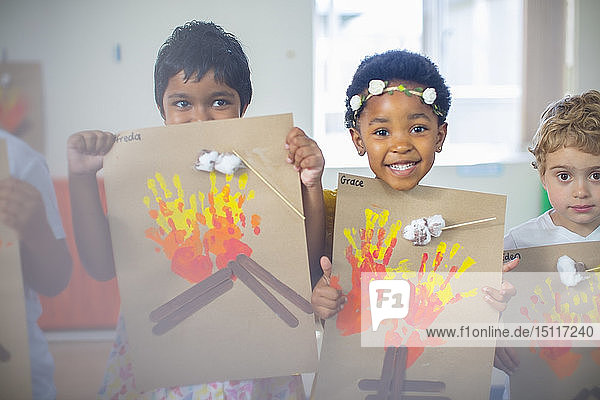Porträt von lächelnden Kindern  die Bilder von Feuer im Kindergarten präsentieren