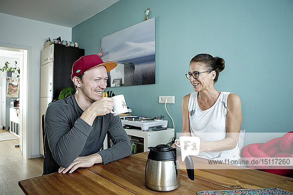 Mutter und Sohn sitzen am Küchentisch und trinken Kaffee
