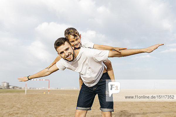 Man carrying boy piggyback on the beach