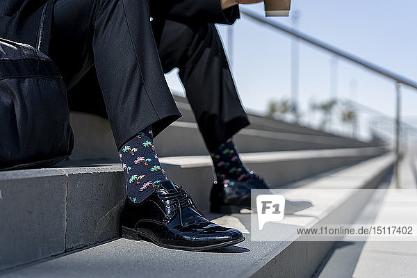 Nahaufnahme eines Geschäftsmannes  der auf einer Treppe sitzt und gemusterte Socken trägt