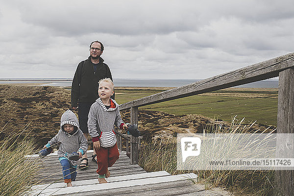 Father and his children walking up stairs among the dunes  Sylt  Germany