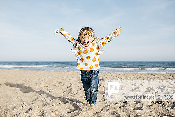 Portrait of happy little girl running on the beach