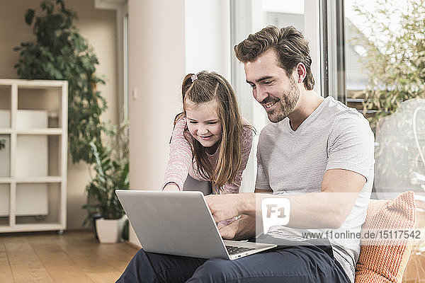 Junger Mann und kleines Mädchen surfen gemeinsam im Netz