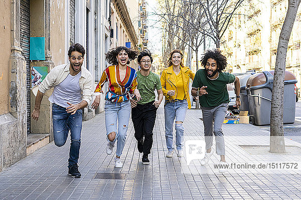 Glückliche Gruppe von Freunden amüsiert sich in der Stadt beim Laufen auf dem Bürgersteig