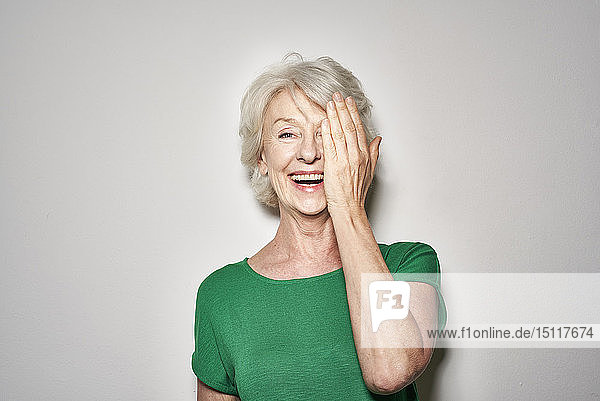 Porträt einer lachenden  reifen Frau  die das Auge mit der Hand bedeckt