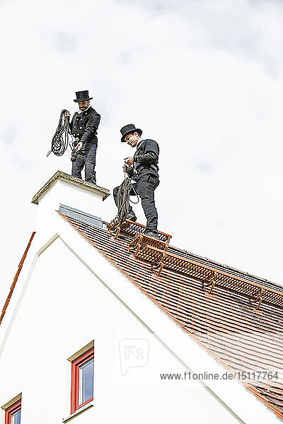 Zwei Schornsteinfeger arbeiten auf dem Hausdach