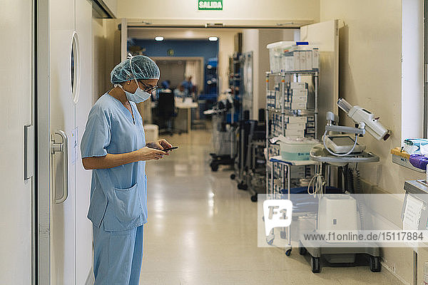 Ärztin  die im Krankenhaus ein Smartphone benutzt und sich auf eine Operation vorbereitet