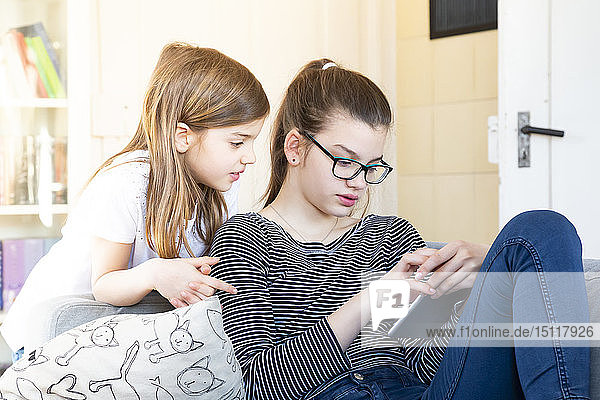 Zwei Schwestern schauen sich zu Hause ein digitales Tablet an