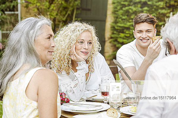 Fröhliche Familie beim gemeinsamen Essen im Garten