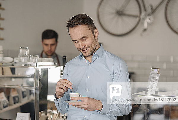 Geschäftsmann trinkt frischen Kaffee in einem Café und lächelt