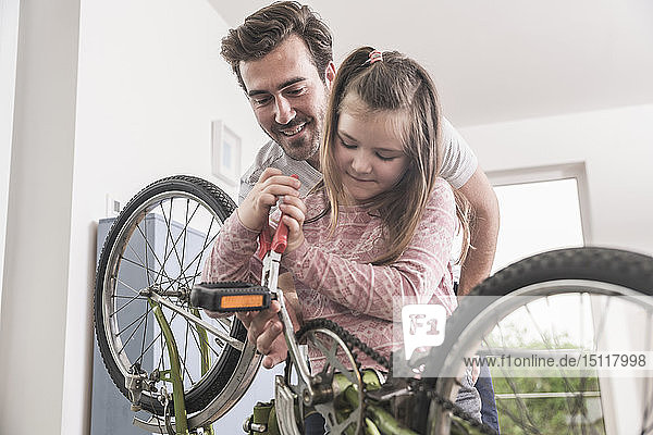 Junger Mann und kleines Mädchen reparieren gemeinsam Fahrrad