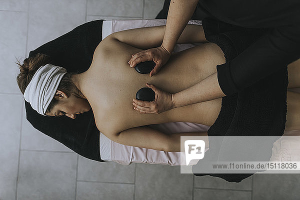 Woman laying on stomach enjoying a spa treatment on her back in spa center