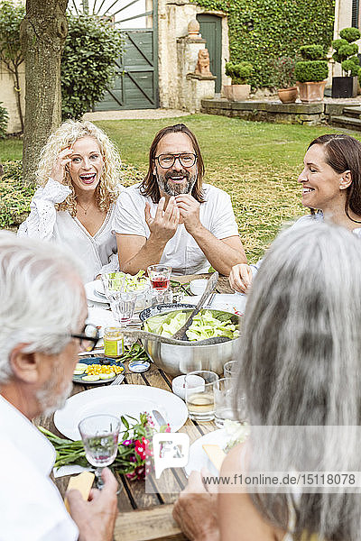Fröhliche Familie beim gemeinsamen Essen im Garten